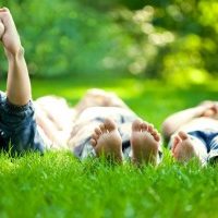 Group of happy children lying on green grass outdoors in spring park
