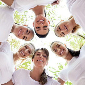 Group of women standing in the circle, smiling at the camera, low angle view.