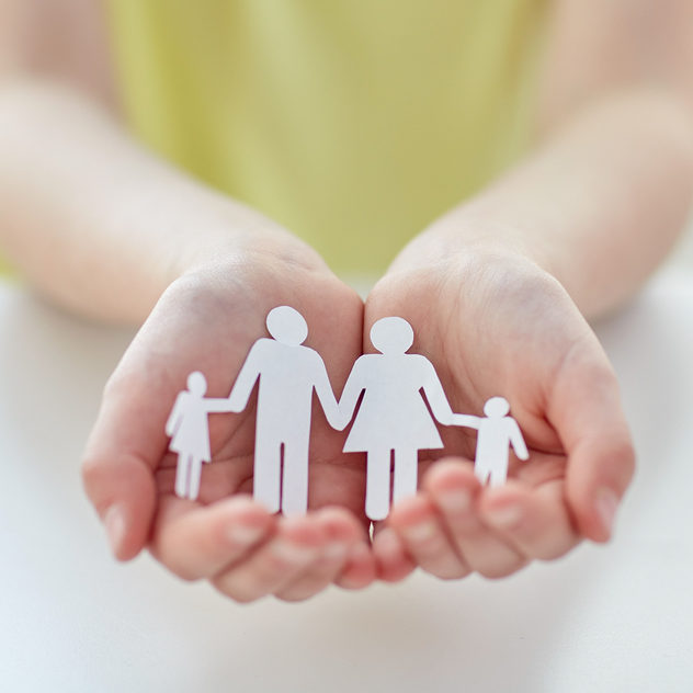 people, charity and care concept - close up of child hands holding paper family cutout at home