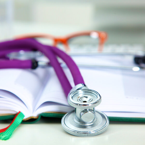 Stethoscope lying on a table on an open book.